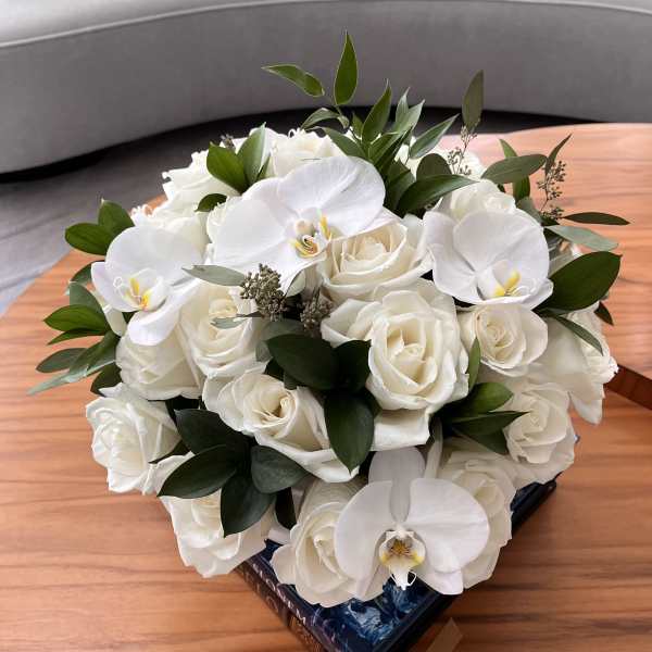White roses and orchids arranged in a low bouquet