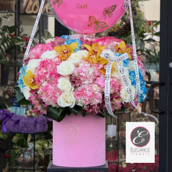Pink balloon-topped flower arrangement with roses, hydrangeas, and orchids