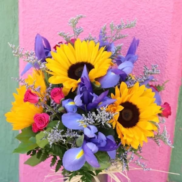 Bouquet of sunflowers, purple irises, and pink roses in a vase