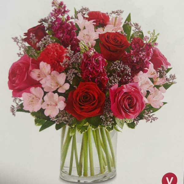 Bouquet of red and pink roses with pale pink flowers in a glass vase