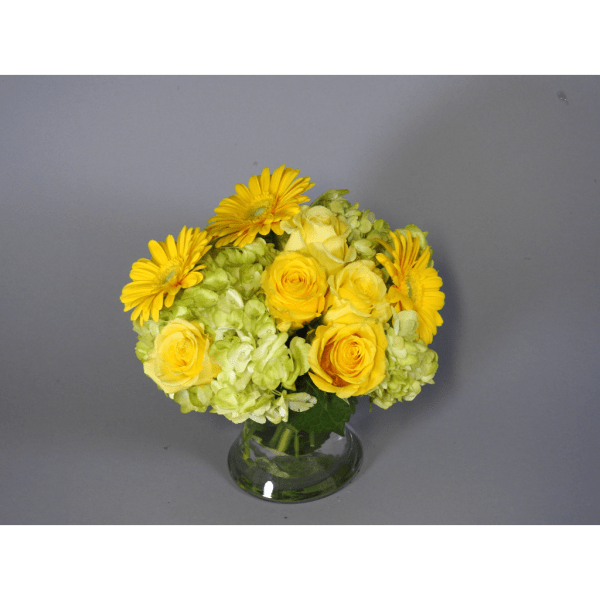 Yellow roses and gerbera daisies in a glass vase