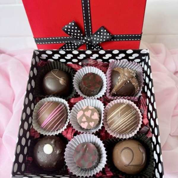 Box of assorted chocolates with a red lid and black ribbon