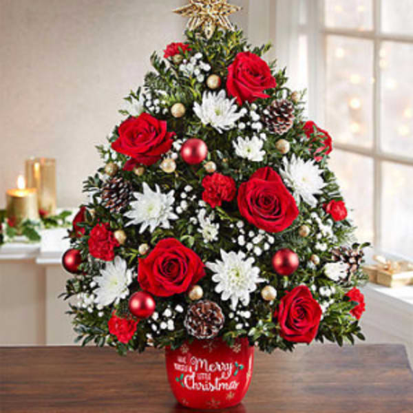 Christmas tree arrangement with red roses and white flowers in a red pot