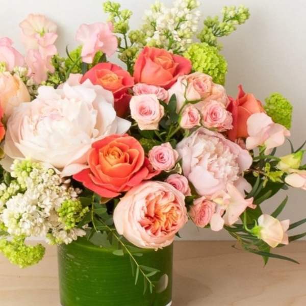 Pink and coral roses arranged in a green glass vase