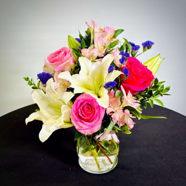 Bouquet of pink roses, white lilies, and pink alstroemeria in a glass vase