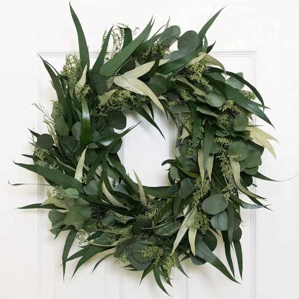 Green foliage wreath with eucalyptus and long leaves on a white door
