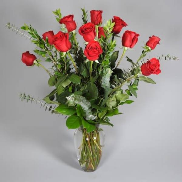 Tall arrangement of long-stemmed red roses in a clear glass vase