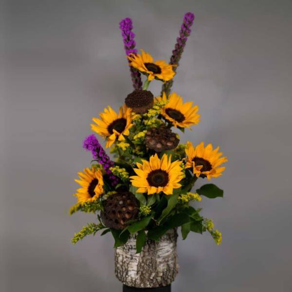 Sunflowers and purple spikes arranged in a birch bark container