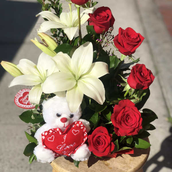 Bouquet of red roses and white lilies with a teddy bear holding a heart