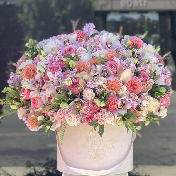 Large pink and white mixed flower arrangement in a round box