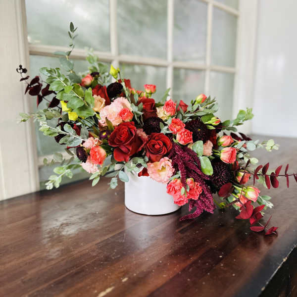 Mixed red and pink floral arrangement in a white vase