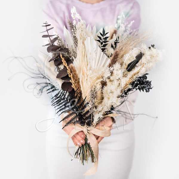 Dried bouquet with beige pampas grass and dark foliage tied with a ribbon