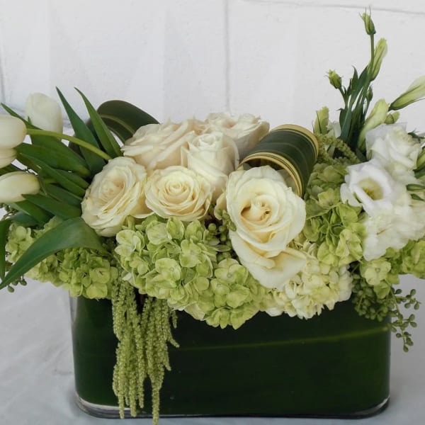 White roses and tulips arranged in a dark green vase