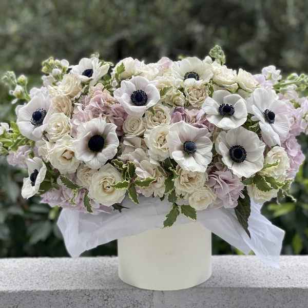 White and blush floral arrangement in a white vase