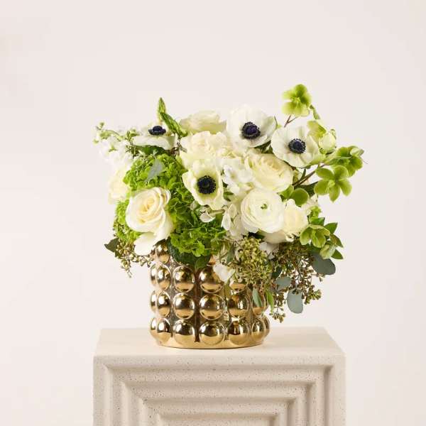 White and green floral arrangement in a gold textured vase