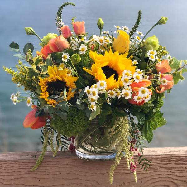 Mixed bouquet with sunflowers, roses, and daisies in a glass vase