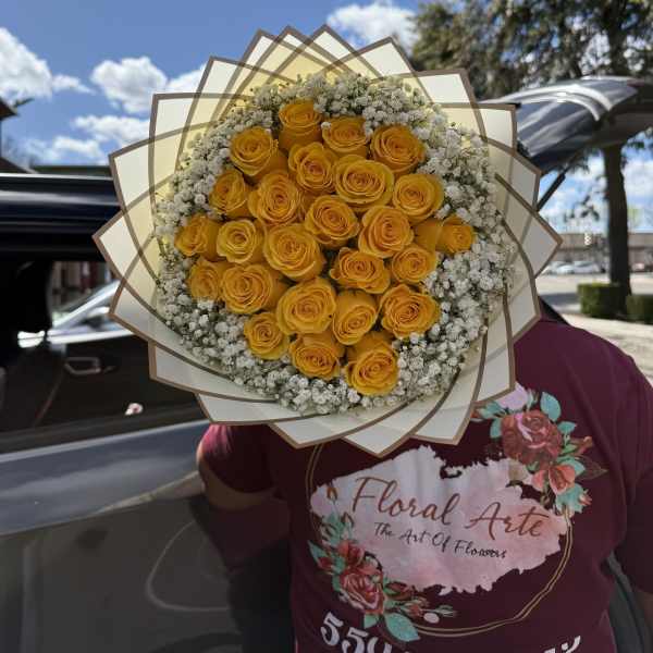 Bouquet of yellow roses with white filler flowers wrapped in layered paper
