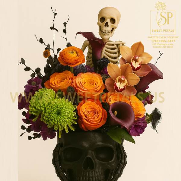 Halloween floral arrangement in a black skull vase with a skeleton topper