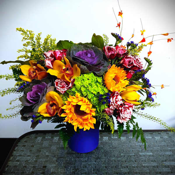 Bright mixed bouquet in a blue vase with sunflowers and orchids