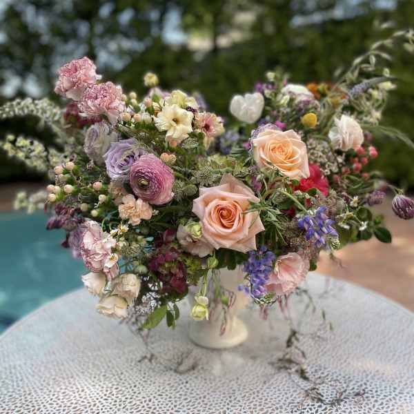 Mixed pastel flower arrangement in a white pedestal vase