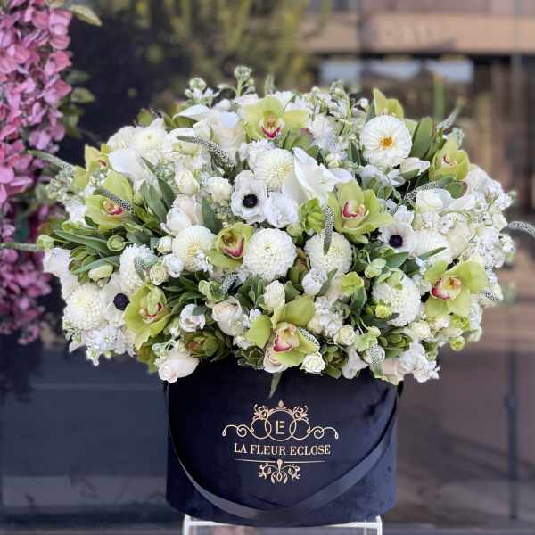 Large white and green floral arrangement in a black hatbox