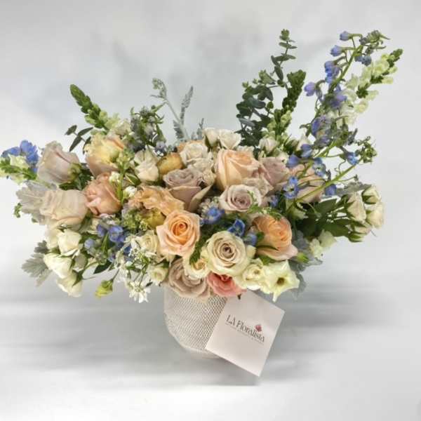 Pastel rose bouquet in a textured vase with blue accents