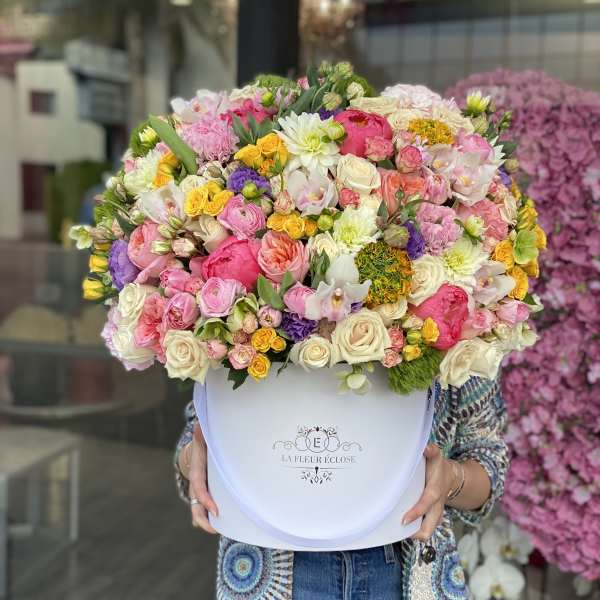 Large mixed bouquet in a white hatbox with pink, white, yellow, and purple flowers
