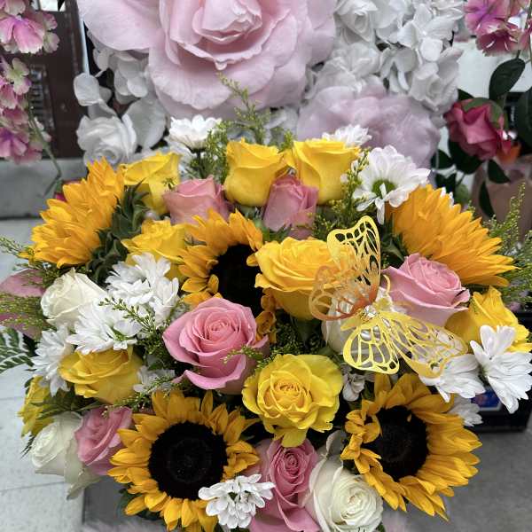 Bouquet of yellow sunflowers, pink and white roses, and white daisies