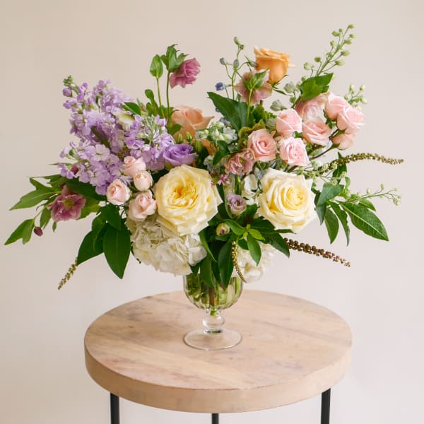 Mixed pastel roses and purple blooms in a glass vase