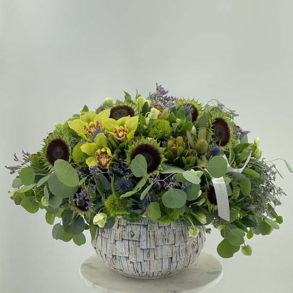 Large green floral arrangement in a textured white vase