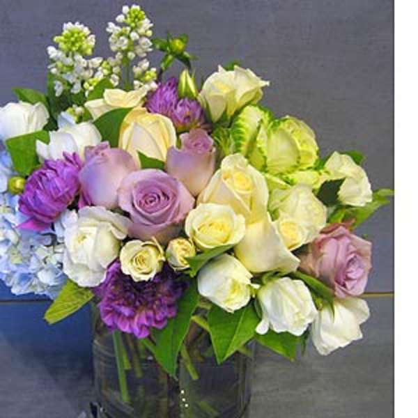 Mixed bouquet of roses, calla lilies, and hydrangeas in a glass vase
