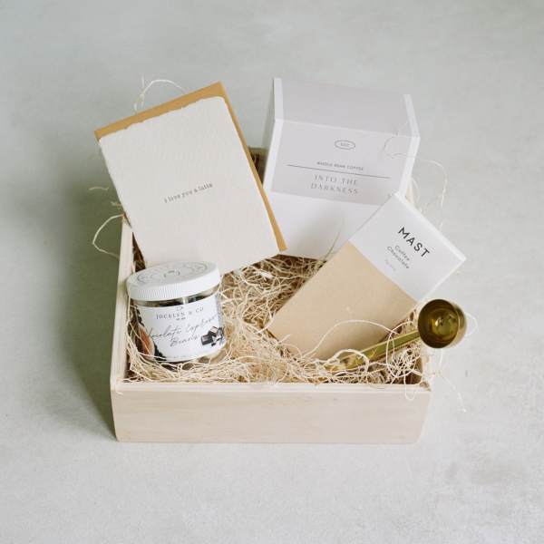 Gift box with coffee and chocolate items in a wooden tray