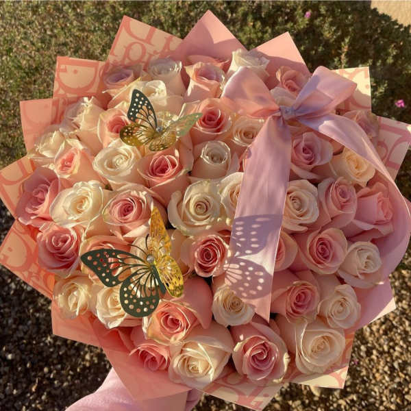 Bouquet of pale pink and cream roses with a pink ribbon and butterfly decorations