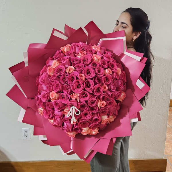 Large bouquet of pink and peach roses wrapped in bright pink paper