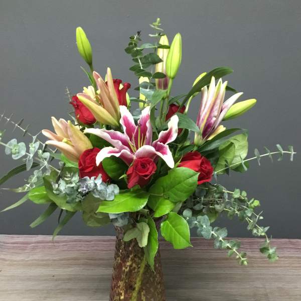 Bouquet of red roses and pink lilies in a glass vase