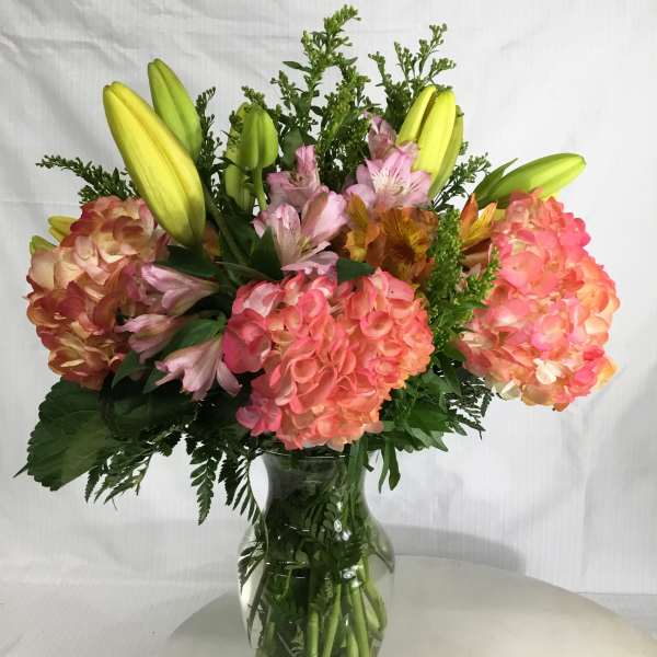 Bouquet of pink hydrangeas and yellow lilies in a glass vase