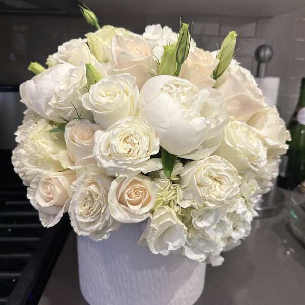 White and blush roses arranged in a white hatbox