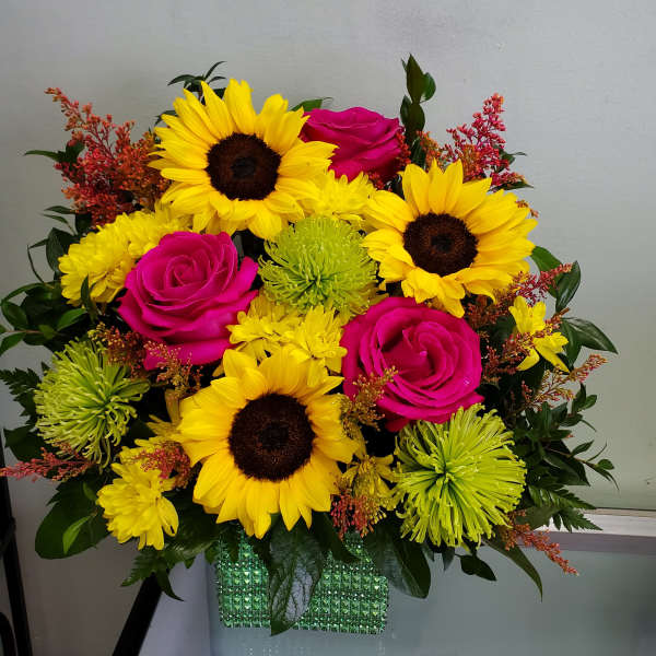 Bouquet of sunflowers, hot pink roses, and green chrysanthemums in a glittery vase