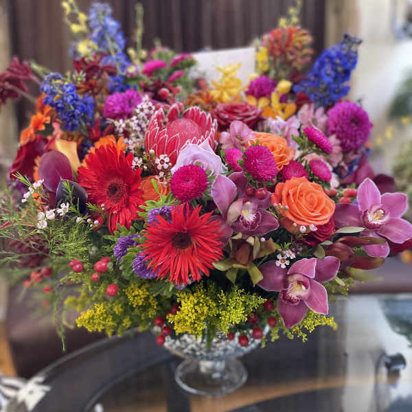 Colorful mixed bouquet with roses, orchids, and gerbera daisies in a glass vase