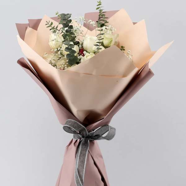 Bouquet of white roses and baby's breath wrapped in pink paper