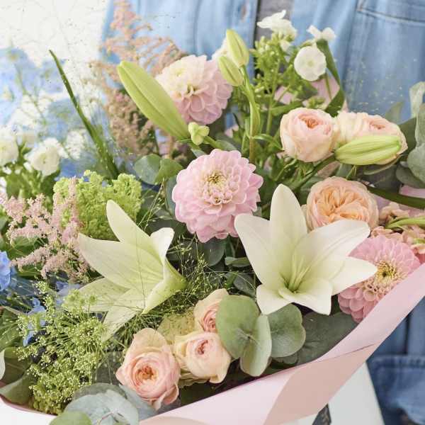 Pastel bouquet with lilies, roses, and pink blooms wrapped in pink paper
