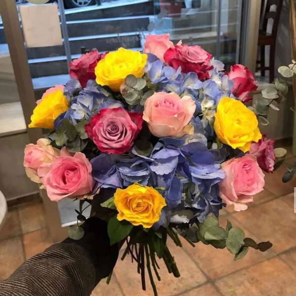 Bouquet of multicolored roses with blue hydrangeas and eucalyptus