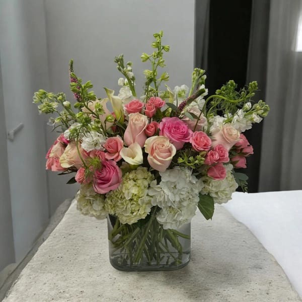 Pink and white roses with hydrangeas in a clear glass vase