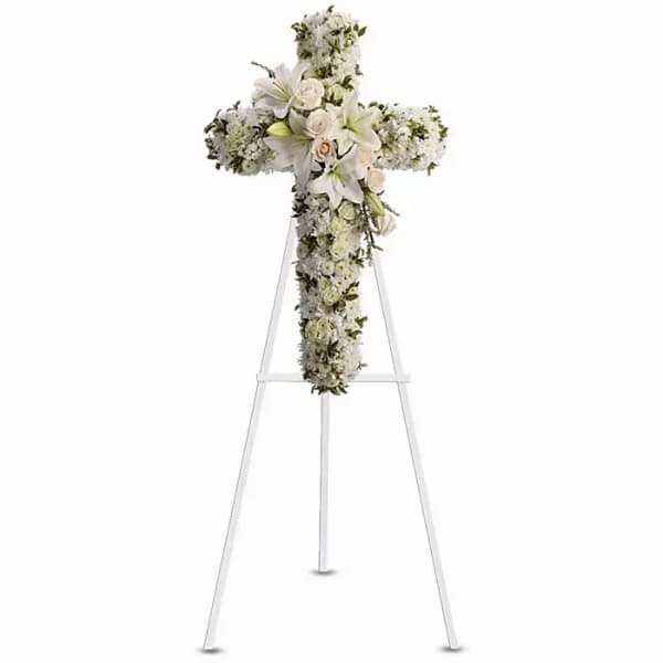 White floral cross arrangement on a stand with lilies and roses