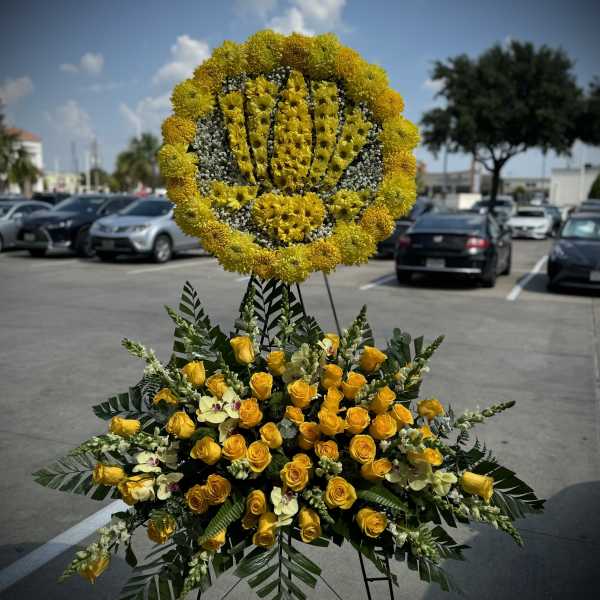 Large yellow floral standing tribute on an easel with roses and orchids
