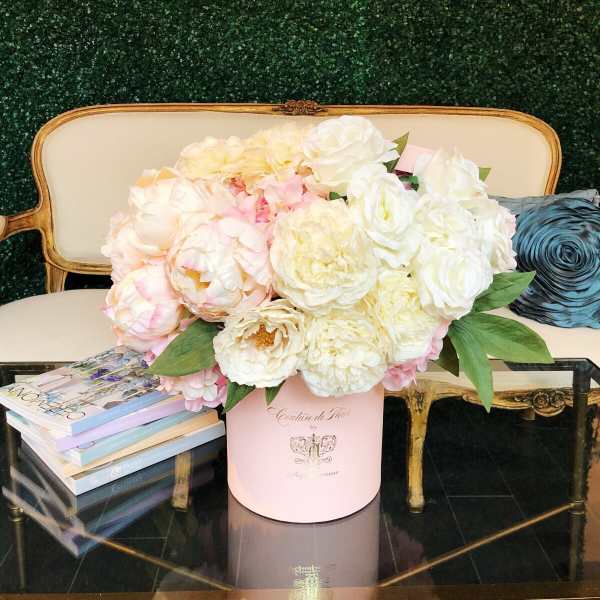 Pink and white flower arrangement in a round box on a table