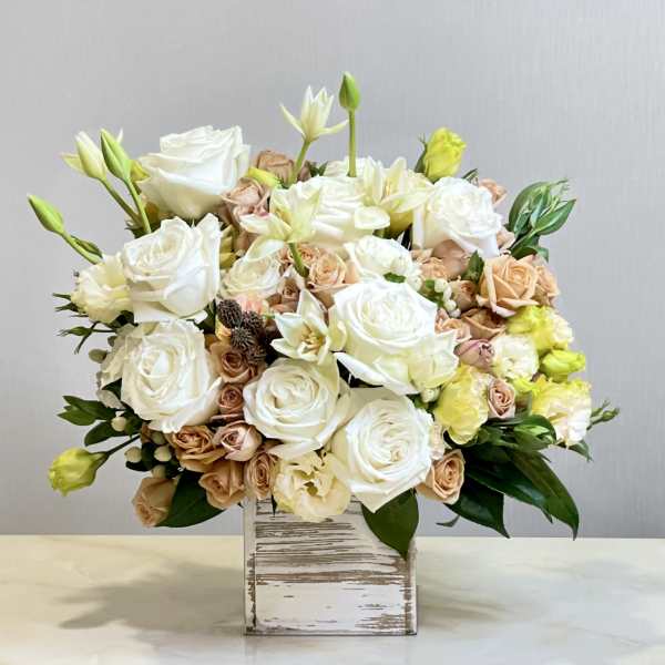 White and blush roses arranged in a rustic wooden box