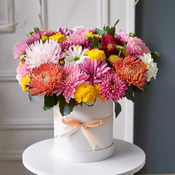Colorful chrysanthemum arrangement in a white hat box with a peach ribbon