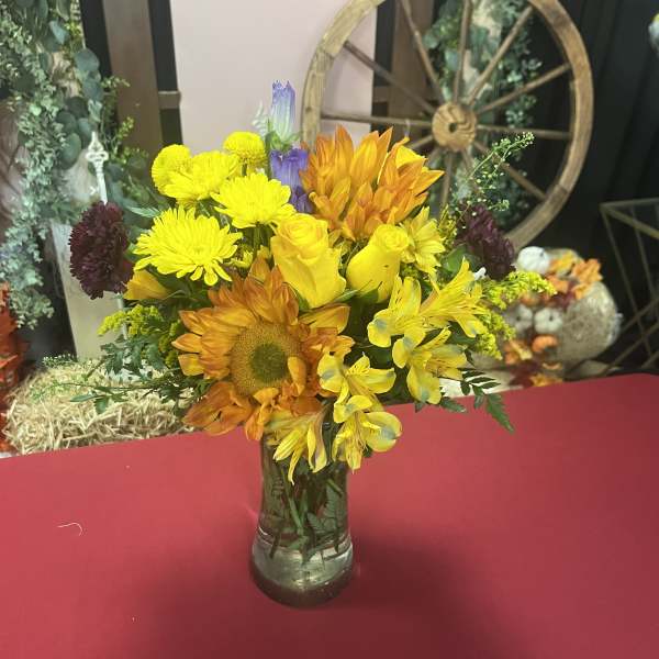 Bright yellow and orange mixed bouquet in a clear glass vase