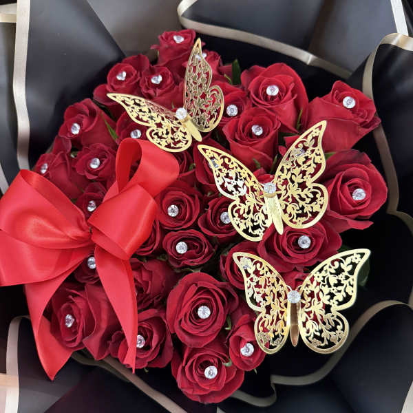 Red rose bouquet with gold butterfly decorations and a red ribbon